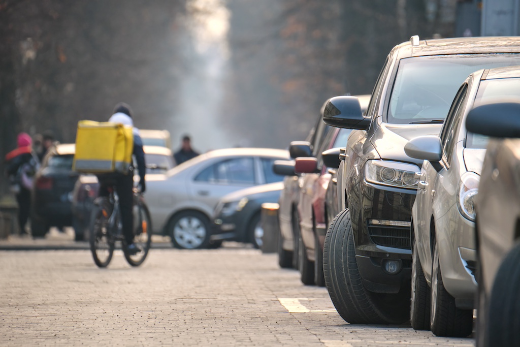 city traffic with cars parked in line on street