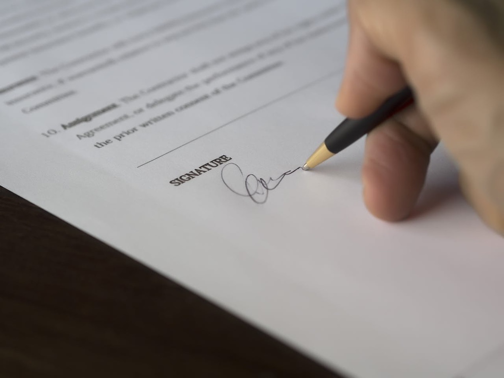 person hand signing on paper