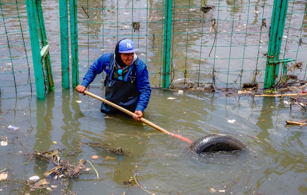 worker clearing debris from polluted floodwater