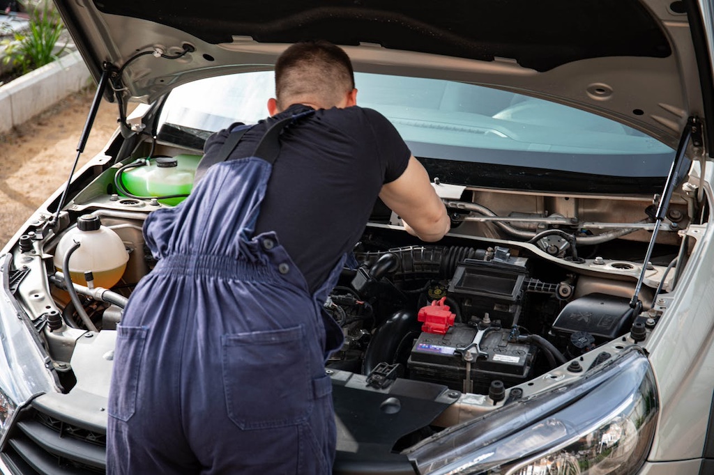 man in black crew t shirt fixing a car