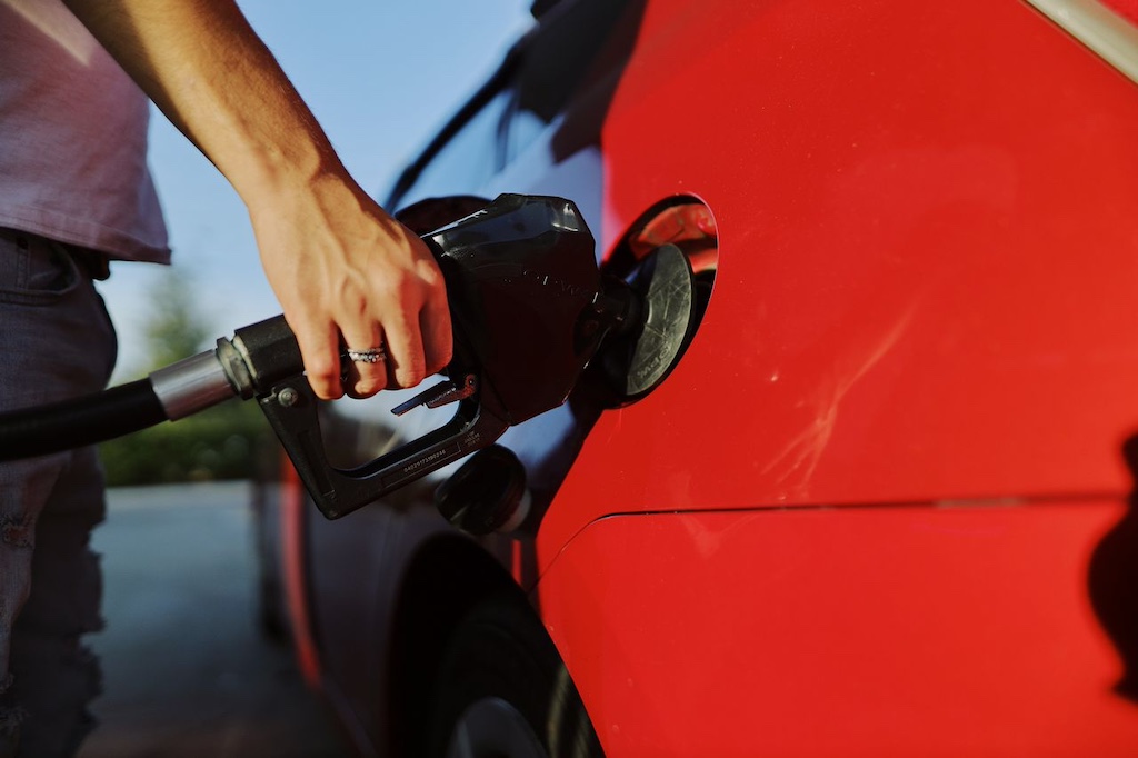 a person hand filling up a red car with gas